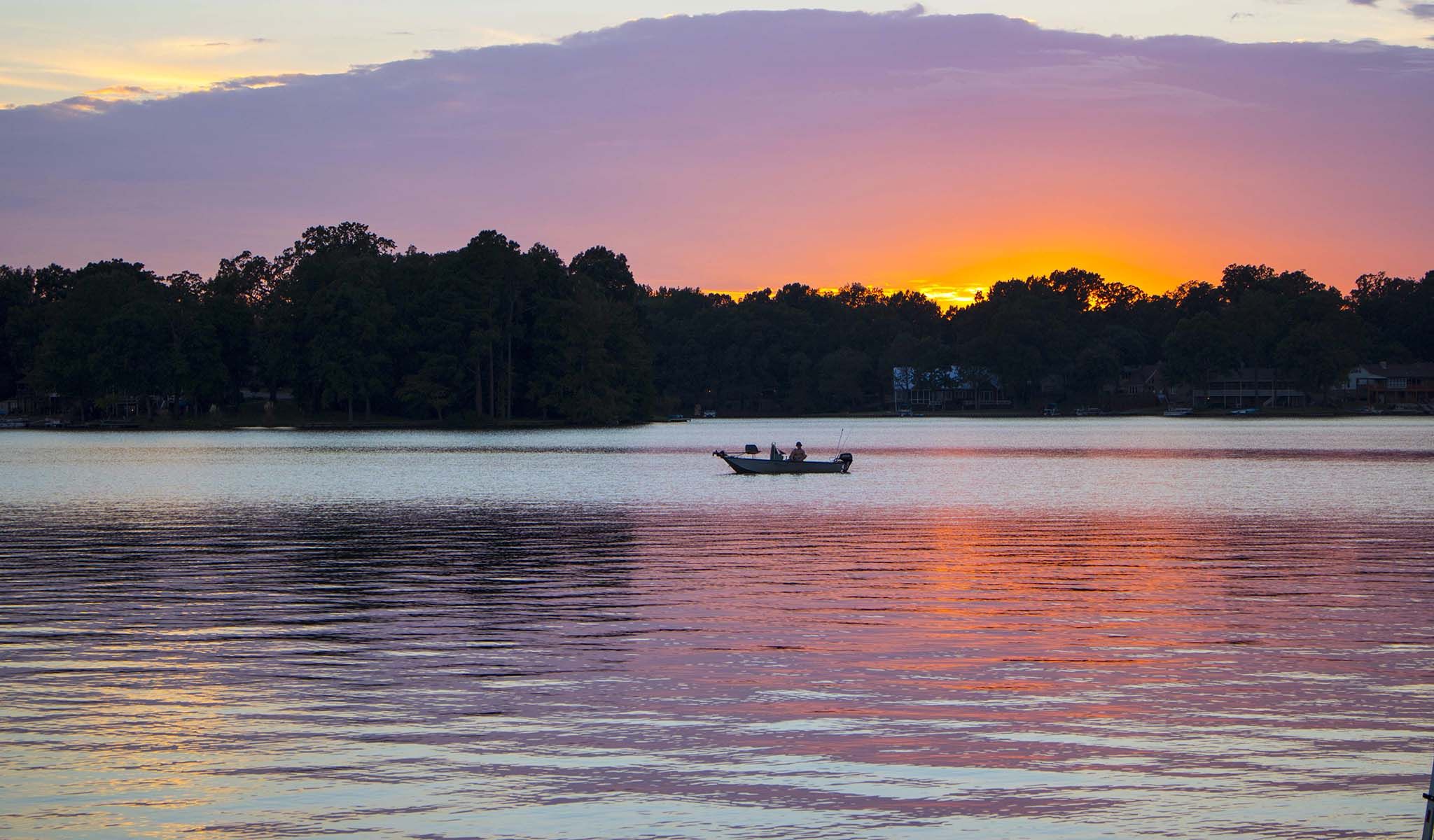 a fisherman in the sunset on Garner Lake in Lakeland TN