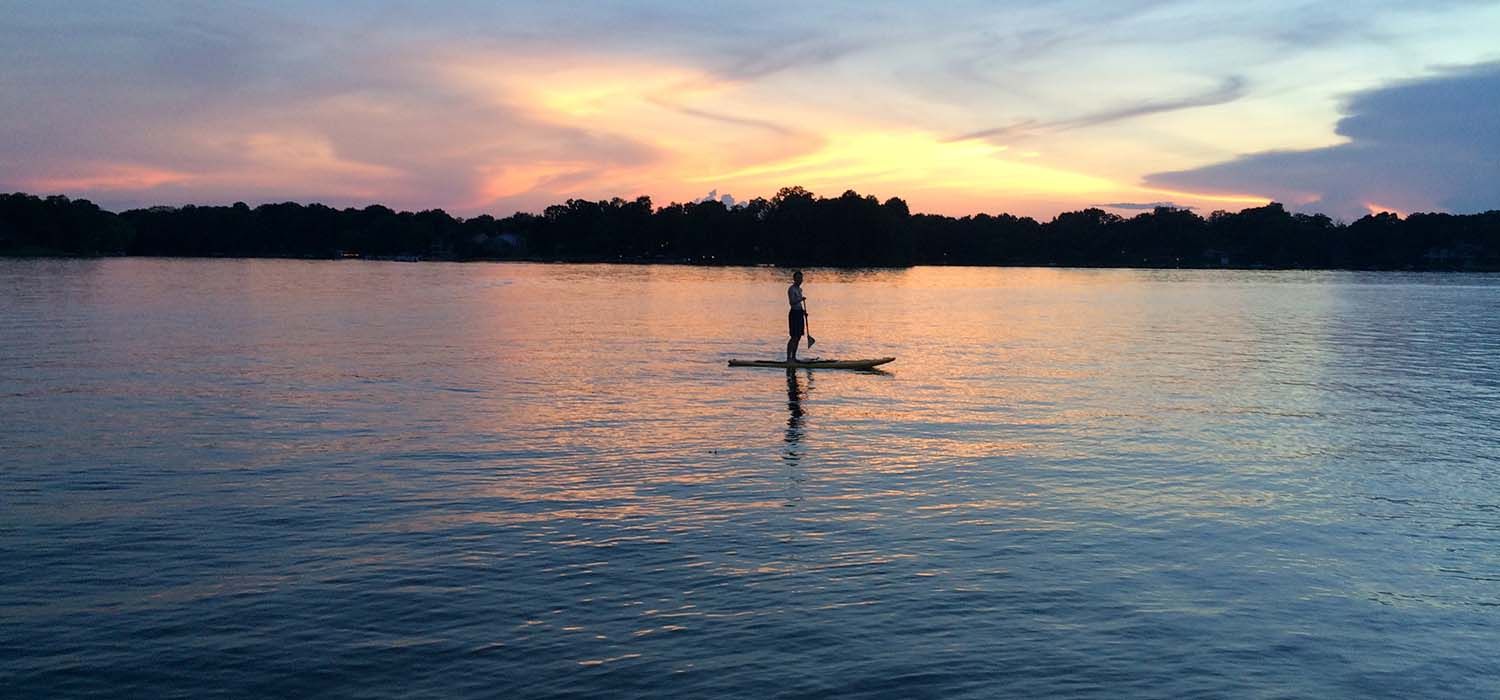 a paddleboarder in a lake sunset